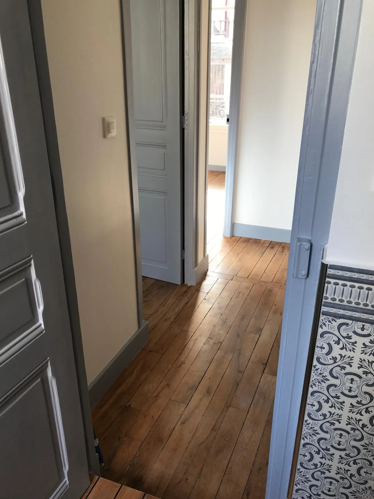Couloir avec parquet et portes peintes en gris bleu.