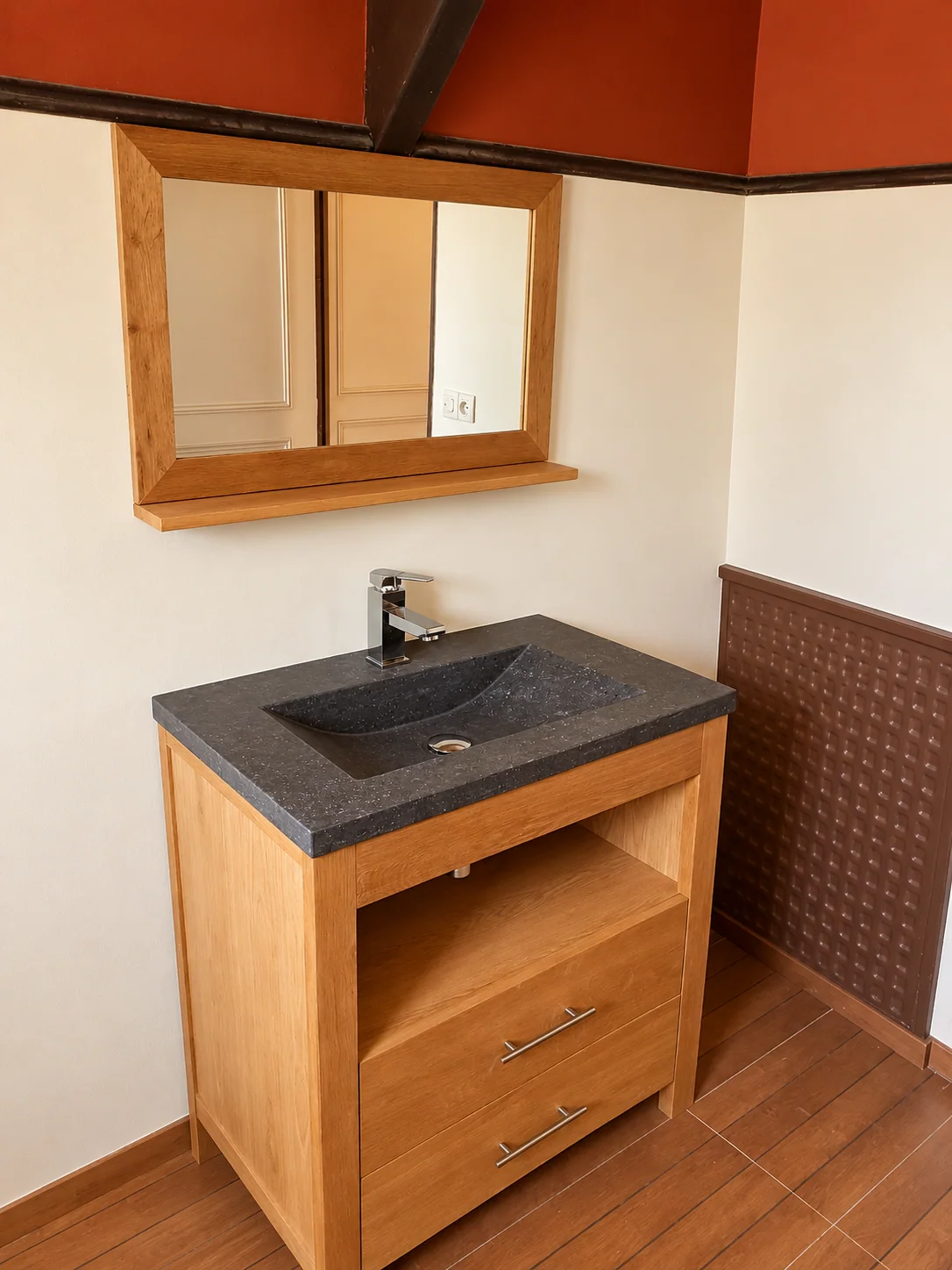 Meuble vasque aspect bois, vasque sombre et miroir avec encadrement bois.