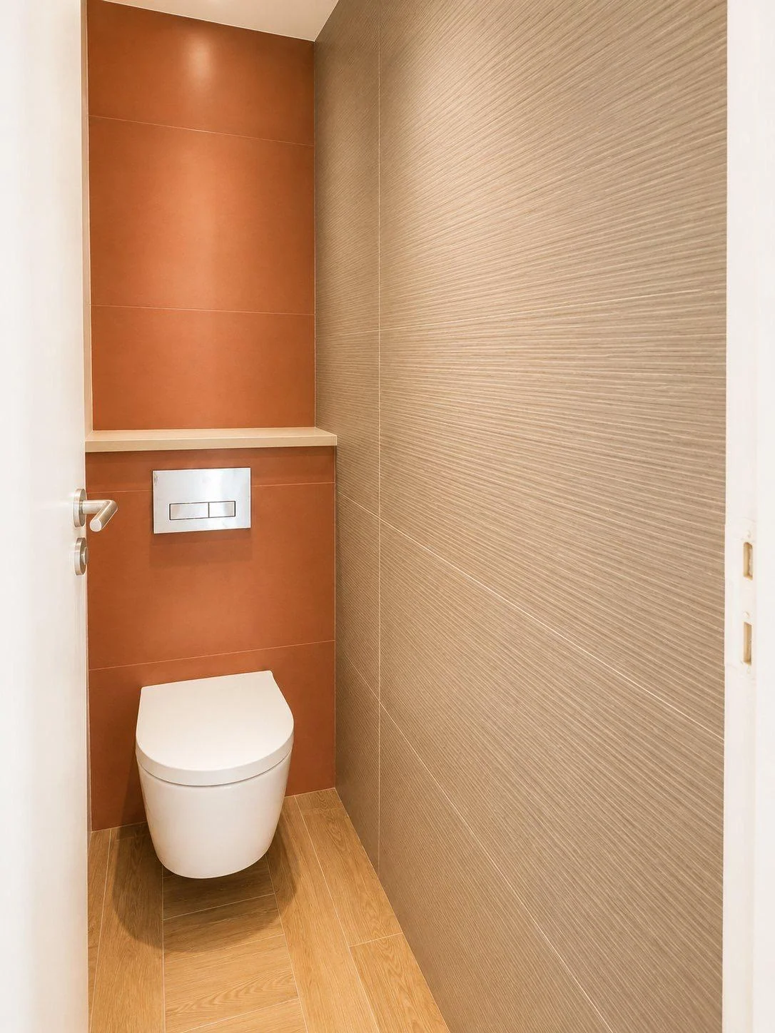 WC suspendu blanc avec paroi orangée et mur latéral texturé.